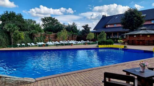 a large swimming pool with chairs and a house at Hotel Karczma u Macieja in Bolków