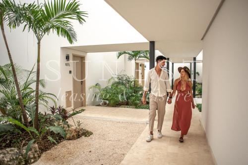 ein Mann und eine Frau gehen in ein Haus in der Unterkunft Hunab Tulum in Tulum
