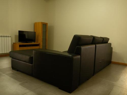 a black leather couch in a living room with a television at Casa Malagueira in Fafião