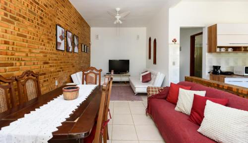 ein Wohnzimmer mit einem roten Sofa und einer Ziegelwand in der Unterkunft Village Itaúna Inn in Saquarema