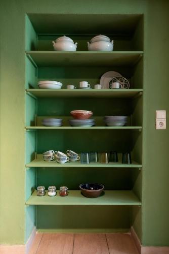 a green cabinet filled with dishes and bowls on shelves at Bodensee Apartments, Sauna, Lake Walks, Free Parking, Self Checkin, Nature Reserve, Restaurants Nearby in Gaißau