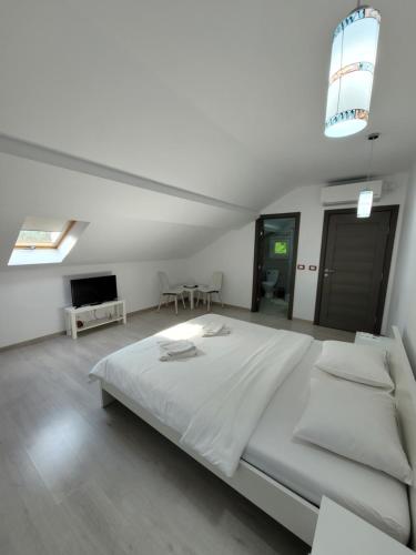 a white bedroom with a large bed and a tv at Casa Patryk in Orşova