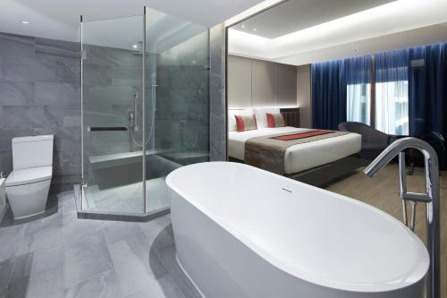 a bathroom with a tub and a bed and a shower at Grace At Five by Grace Hotel Bangkok in Bangkok