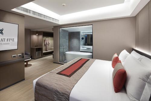 a bedroom with a large bed and a bathroom at Grace At Five by Grace Hotel Bangkok in Bangkok