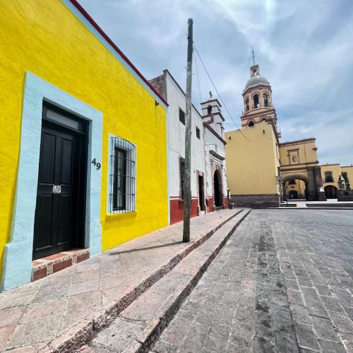 uma rua vazia com um edifício amarelo e uma igreja em Hostal Luna 49 em Querétaro