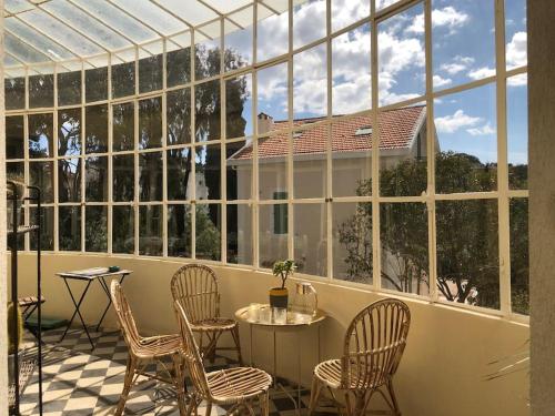 a conservatory with chairs and a table in front of a large window at Villa - Toulon/La Mitre - plages à pied - 9 couchages in Toulon