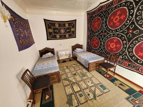 an attic room with two beds and a rug at Zafar Family Guesthouse in Bukhara
