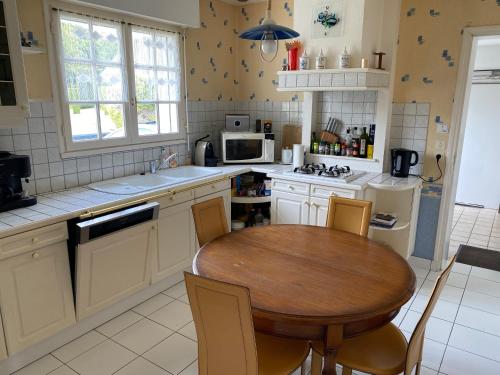 une cuisine avec une table en bois et une petite table avec des chaises dans l'établissement Maison tout confort proche des plages, à Ploemeur