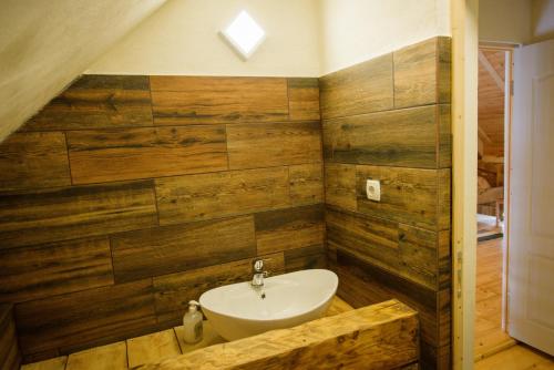 a bathroom with a sink and wooden walls at Válaszút Fogadó in Păuleni-Ciuc