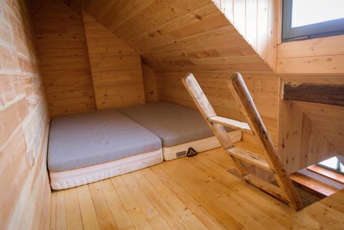 a bed and a chair in a wooden room at Válaszút Fogadó in Păuleni-Ciuc