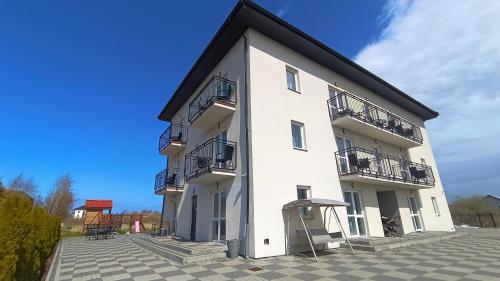 a white building with balconies and a blue sky at Nad Stawem 2 in Sarbinowo