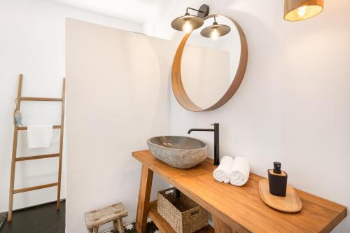 een badkamer met een wastafel en een spiegel aan de muur bij Sensacions Menorca - Villas & Bungalows en complejo Pueblo Menorquín in Son Xoriguer