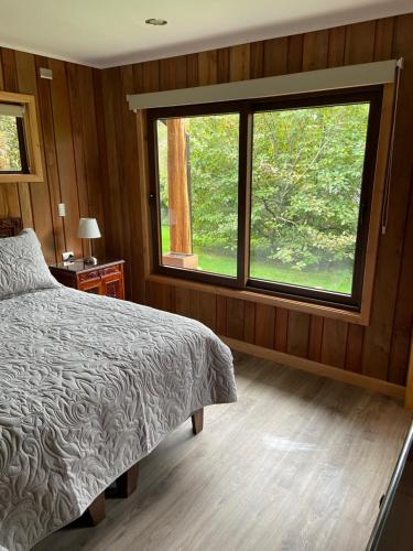 a bedroom with a bed and a large window at Cabañas Peumayen in Puerto Varas