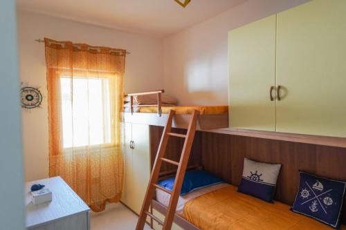 een slaapkamer met een stapelbed, een ladder en een bureau bij Casa Ilaria Calaliberotto in Cala Liberotto