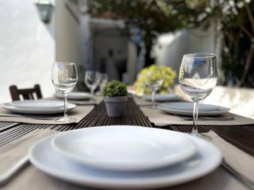 una mesa con platos blancos y copas de vino. en See You Again Caparica, en Costa da Caparica
