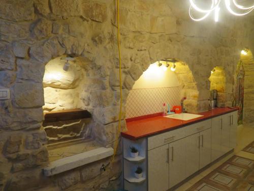 y baño de piedra con lavabo y ducha. en אורות בעתיקה - צימרים ונופש בצפת en Safed