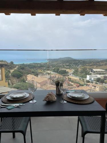 a table with glasses and plates on it with a view at bella vista Villasimius in Villasimius