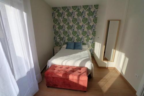 een kleine slaapkamer met een bed met een rode poef bij APARTAMENTOS MESTRE in Ayamonte