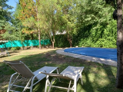 a pair of chairs sitting in the grass next to a pool at Casa de campo El Zoki in Villa Anizacate