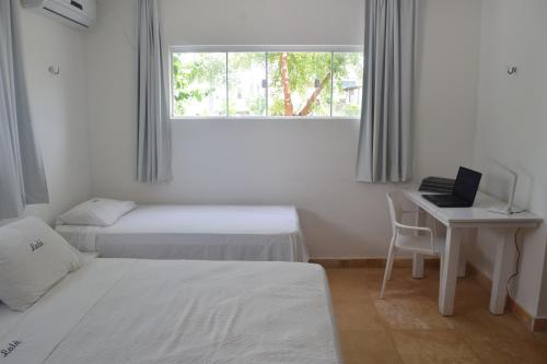 ein Schlafzimmer mit zwei Betten und einem Schreibtisch mit Laptop in der Unterkunft Casa de Lala Beach House in São Miguel do Gostoso