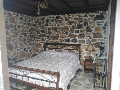sypialnia z łóżkiem w kamiennej ścianie w obiekcie Ελαιώνας - Solar Energy House w mieście Chorefto
