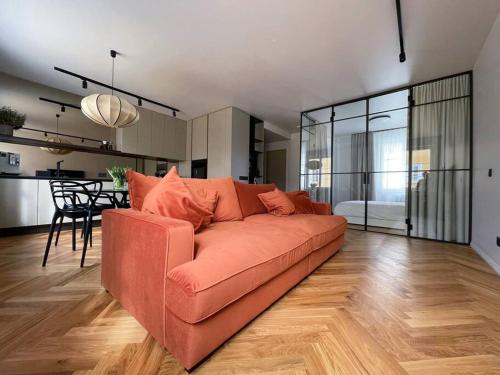 a living room with a orange couch and a kitchen at New Chic & Minimal Old Town Flat in Kuressaare