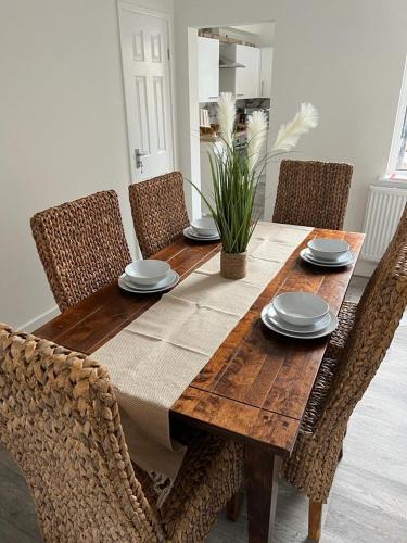 een eettafel met stoelen en een houten tafel met borden bij Rydal house with office space newly refurbished in Newton-le-Willows