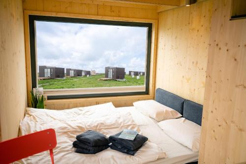 a bed in a room with a large window at Tiny House Nature 1 Innenlage - Green Tiny Village Harlesiel in Carolinensiel