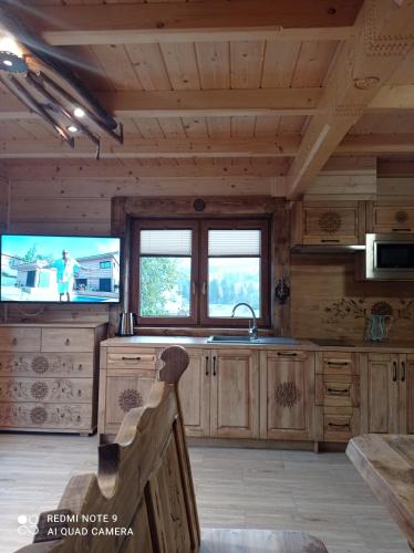 a kitchen with wooden cabinets and a tv in a cabin at Pokoje ,,Goramiba''Jurgów in Jurgów