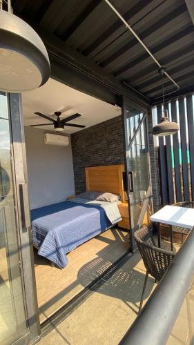 a bedroom with a bed and a balcony with a table at REVU 519 in Tepic