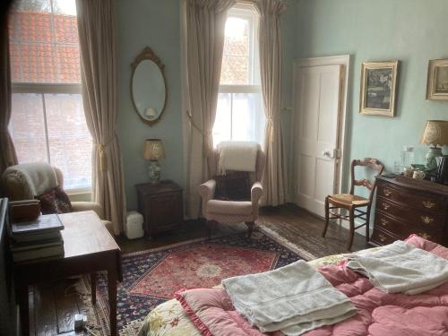 1 dormitorio con cama, silla y espejo en The Old Bakehouse, Walsingham, en Little Walsingham