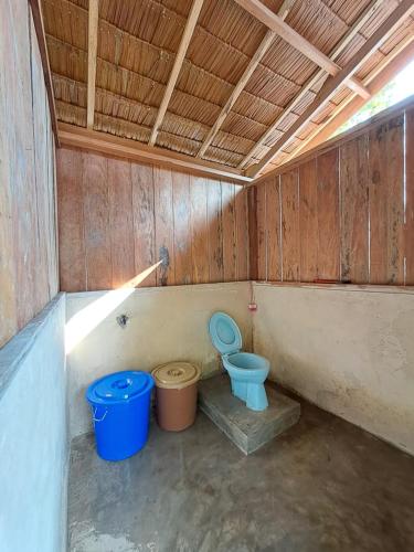 a bathroom with a blue toilet and two buckets at GAM BAY bungalow's in Besir