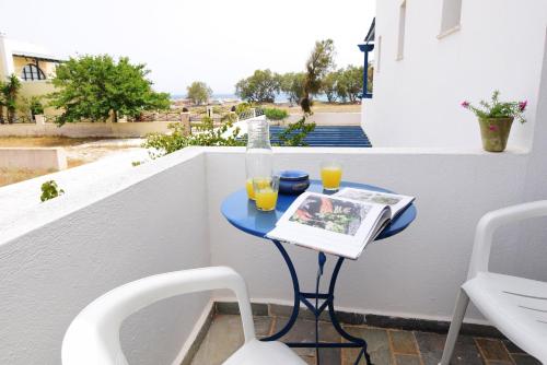 ペリヴォロスにあるThalassitis Coastal Apartmentsの本とオレンジジュース2杯が置かれた青いテーブル