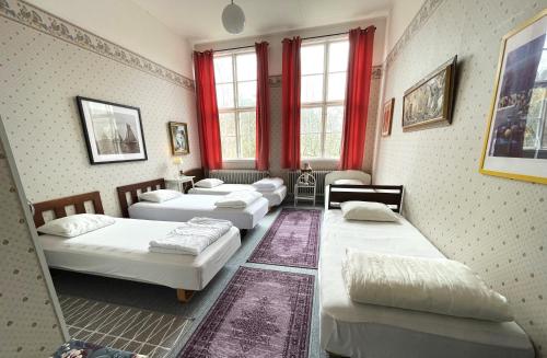 a room with four beds and red curtains at Tivedens Hostel-Vandrarhem in Karlsborg