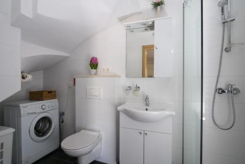 Un baño blanco con lavabo y lavadora. en Apartments Trabakul, en Trogir