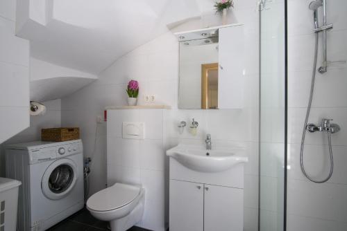 a white bathroom with a sink and a washing machine at Apartments Trabakul in Trogir