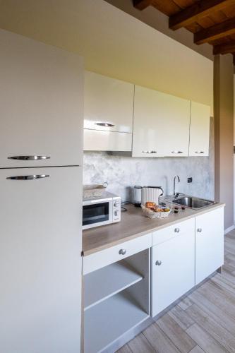 a kitchen with white cabinets and a sink at Angolo Nascosto Apartments in San Fiorano