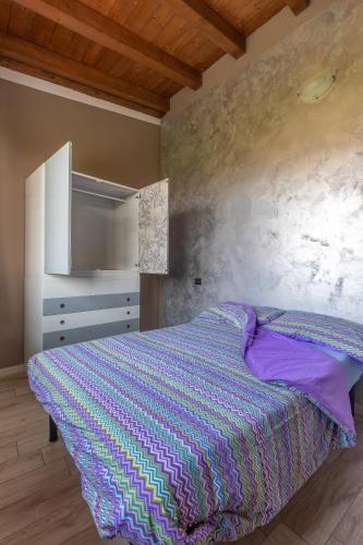 a bedroom with a bed with a purple comforter at Angolo Nascosto Apartments in San Fiorano