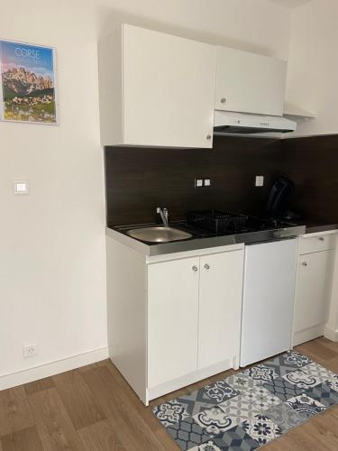 une petite cuisine avec des armoires blanches et un évier dans l'établissement Résidence City Suites Ajaccio, à Ajaccio