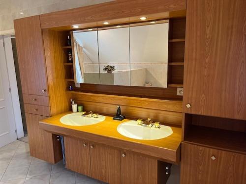een badkamer met 2 wastafels en een grote spiegel bij Villa Haagdoorn te Achel, 10 personen, 12 personen op aanvraag, met zwembad op het zuiden in een oase van rust! in Achel