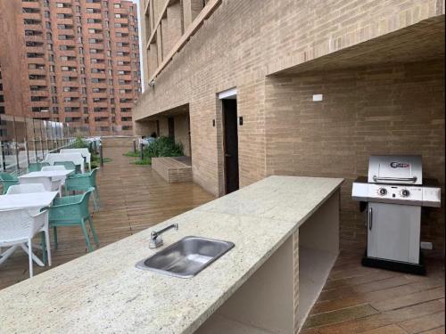 a kitchen with a sink and a counter with tables and chairs at Wohnung Queens Deluxe in Bogotá