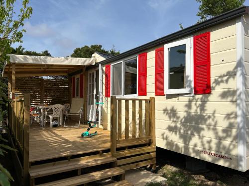 a tiny house with red shutters and a deck at Les mobil homes de Naka, 6 places, TV, CLIM in Port-la-Nouvelle