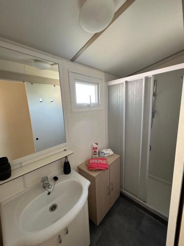 a bathroom with a sink and a mirror and a shower at Les mobil homes de Naka , camping le NOVELA in Port-la-Nouvelle
