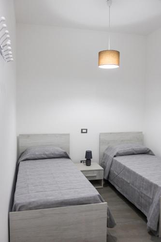 two beds in a room with white walls at Atrepassidalmare in Marina di Ragusa