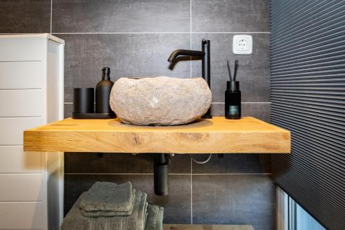 a bathroom with a stone bowl on a wooden shelf at B&B Zijlsterkerk in Munnekezijl