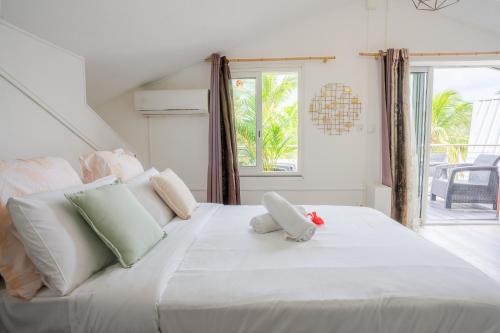a bedroom with a large white bed with a window at Le Sable d'Or in La Saline les Bains