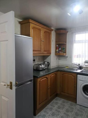 a kitchen with wooden cabinets and a white refrigerator at Shielded Serenity - 3 BR House in South Shields