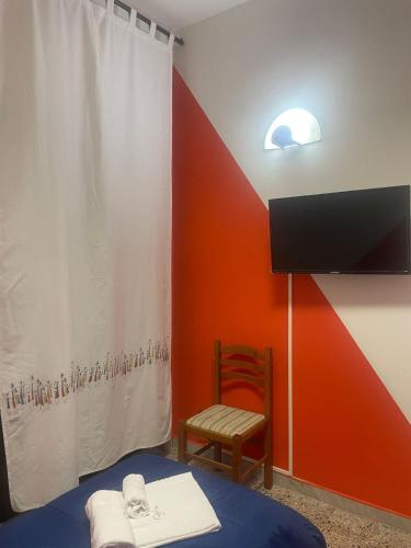 a room with a bed and a tv and a chair at Beteyà Hostel Don Bosco in Catania