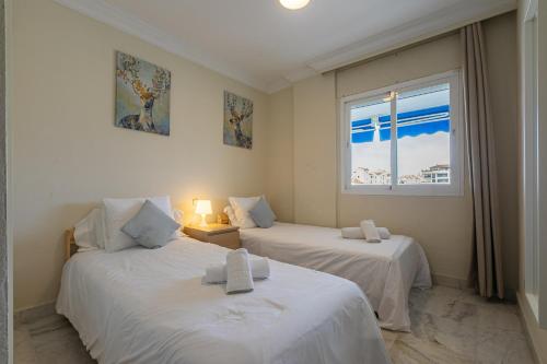 two beds in a room with a window at Puerto Banus, Marina Banus, 2BR, 2BTH, pool, parking, Marbella, 1J in Marbella
