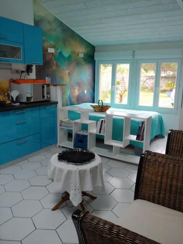eine Küche mit blauen Schränken und einem Tisch im Zimmer in der Unterkunft Studio cocooning in Le Porge